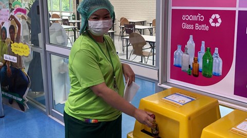 Thai employee throwing waste into a recycling station